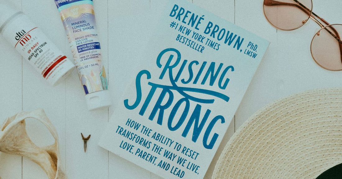 A flatlay of a skincare routine book by Hannah Martin surrounded by serums, moisturisers, and supplements on a marble surface.