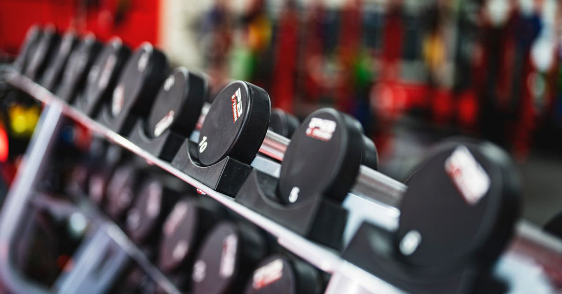 A pair of black dumbbells on a gym floor, representing how to improve shoulder and arm strength with targeted exercises