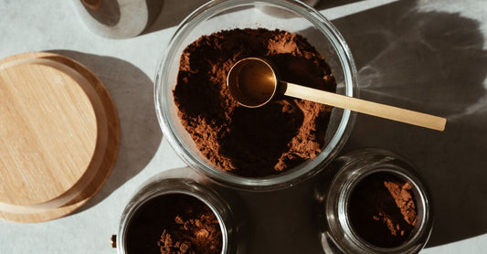 A glass jar of organic maca powder with a wooden scoop on a kitchen counter, illustrating how to use maca powder for energy.