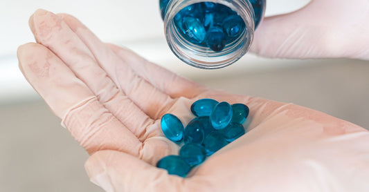 Bottle of blueberry max capsules next to fresh blueberries on a light wooden surface, illustrating natural antioxidant supplementation.