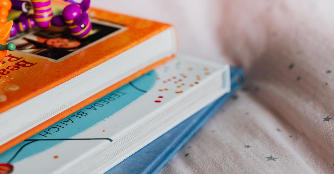 Stack of colourful books on parenting spirited children, with a comforting cup of tea nearby, in a bright UK home setting.