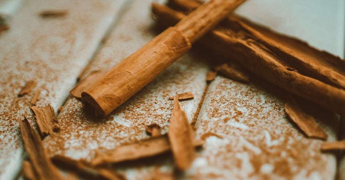 A bowl of fine catuaba bark powder with a wooden scoop on a neutral background, illustrating a natural herbal supplement for vitality and wellness in the UK.