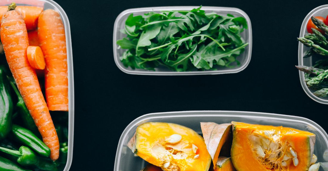 A flat lay of colourful, macro-balanced meals in black containers, illustrating the world’s fittest cookbook recipes for UK fitness enthusiasts.