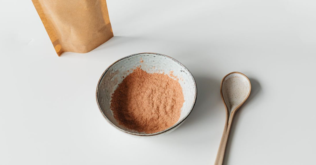 A wooden bowl filled with maca root powder, with a small scoop beside it, representing maca root for energy supplements.